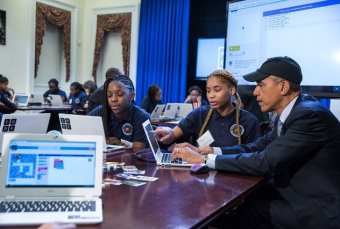 President Obama visits with students and engaging in coding during the